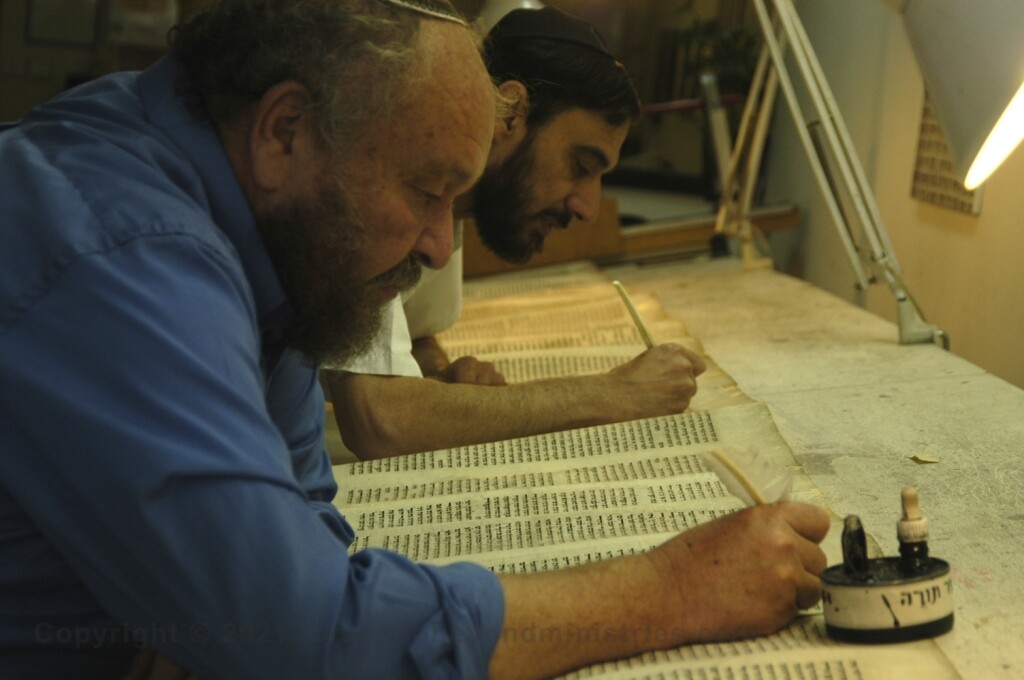 Two Soferim repairing letters on  a Torah Scroll at Macon OT in Jerusalem